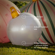 White inflatable ball with features highlighted on a grassy background. Text reads oversized design, indoor/outdoor use. weighted base and ground stakes